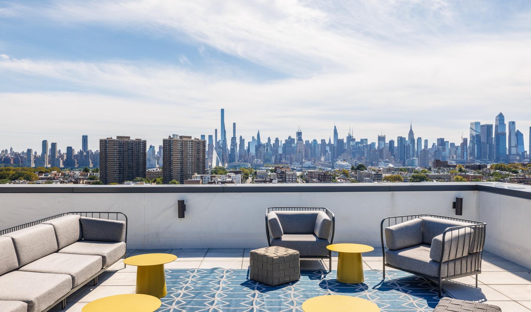 a rooftop lounge area with a couch, chairs and tables